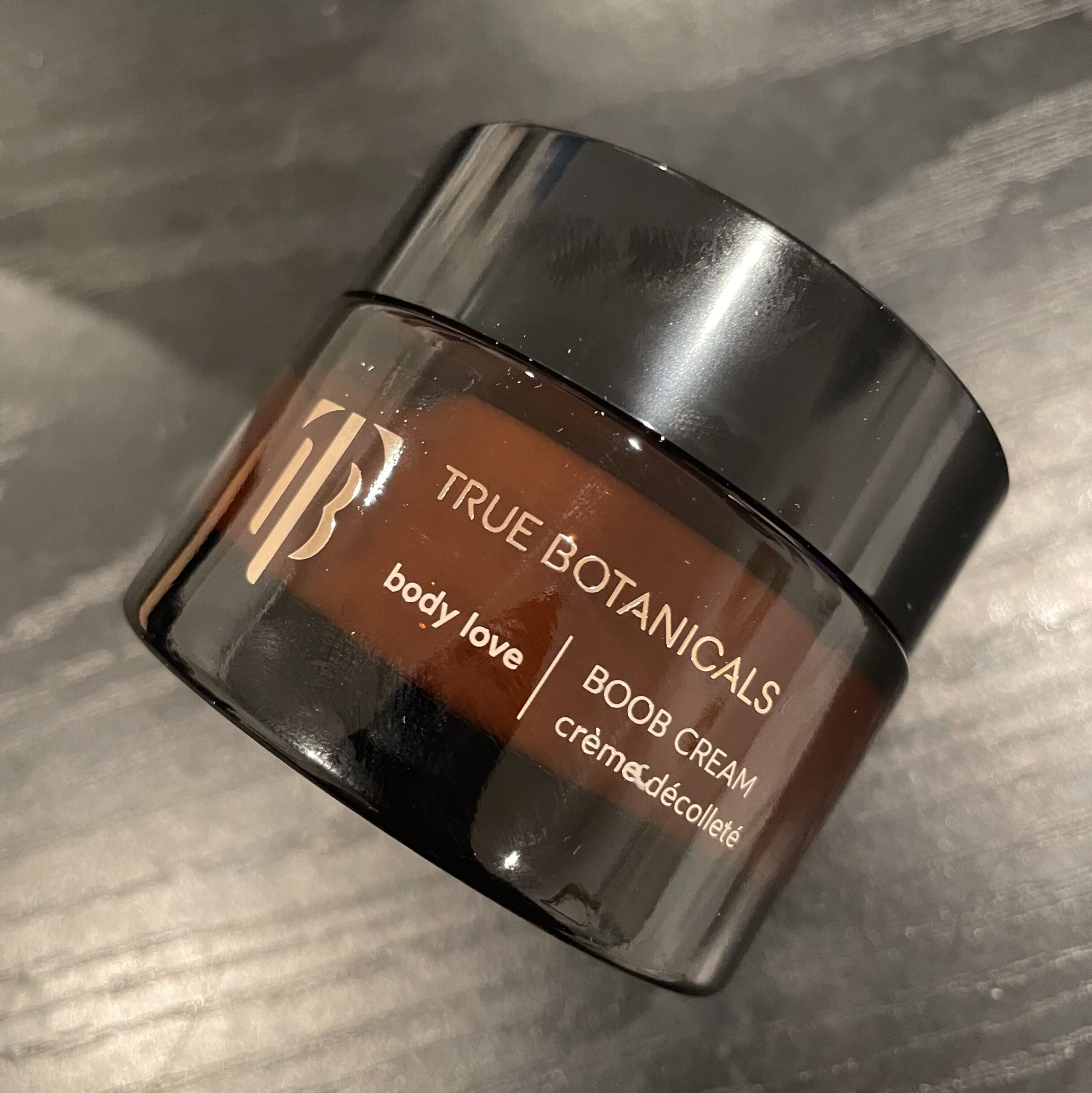 A jar of True Botanicals body cream on a table.