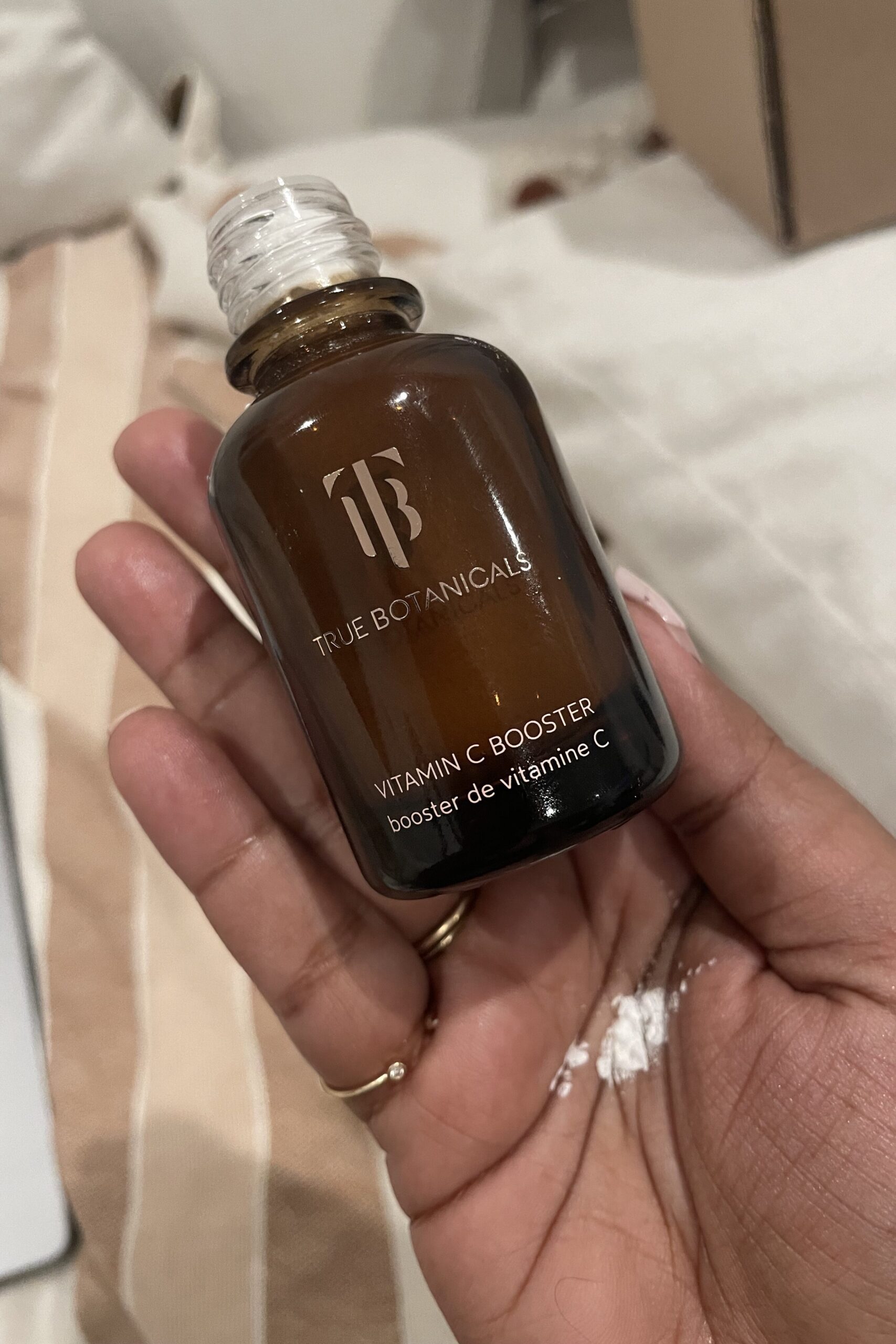 A person holding a small bottle of true botanicals oil.
