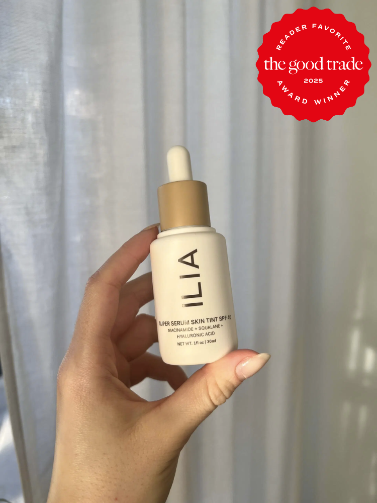 A hand holds a bottle of Ilia Super Serum Skin Tint with SPF 40. A red badge on the image proudly declares it "AlsWell Blog 2025 Reader Favorite Award Winner.
