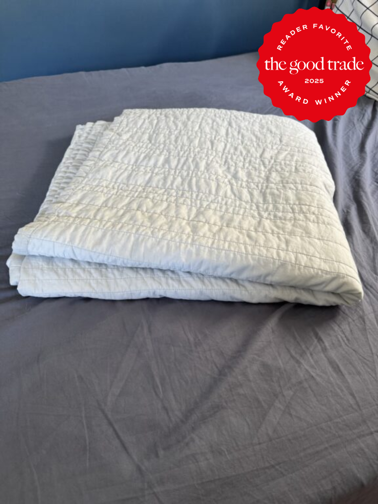 A folded, white quilt lies on a bed with gray sheets. A red badge in the top right corner reads "Reader Favorite, AlsWell Blog, Award Winner, 2025.