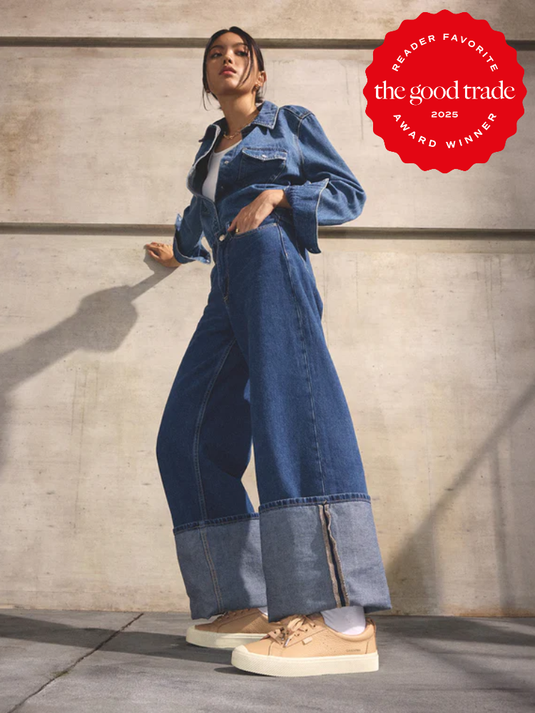 Woman wearing a denim jacket, wide-leg jeans, and sustainable sneakers stands against a concrete wall; "AlsWell Blog 2025 Award Winner" badge appears in the top right corner.
