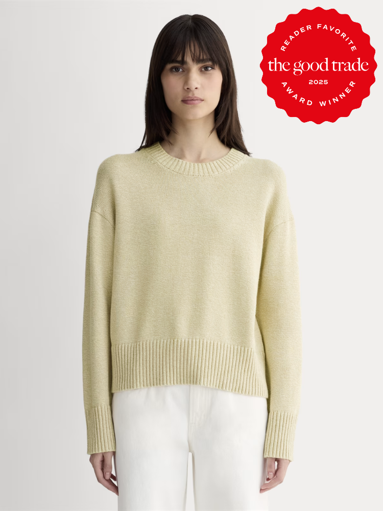 Woman wearing a light yellow knit sweater and white pants stands against a plain background; a red award badge from AlsWell Blog is displayed in the top right corner.